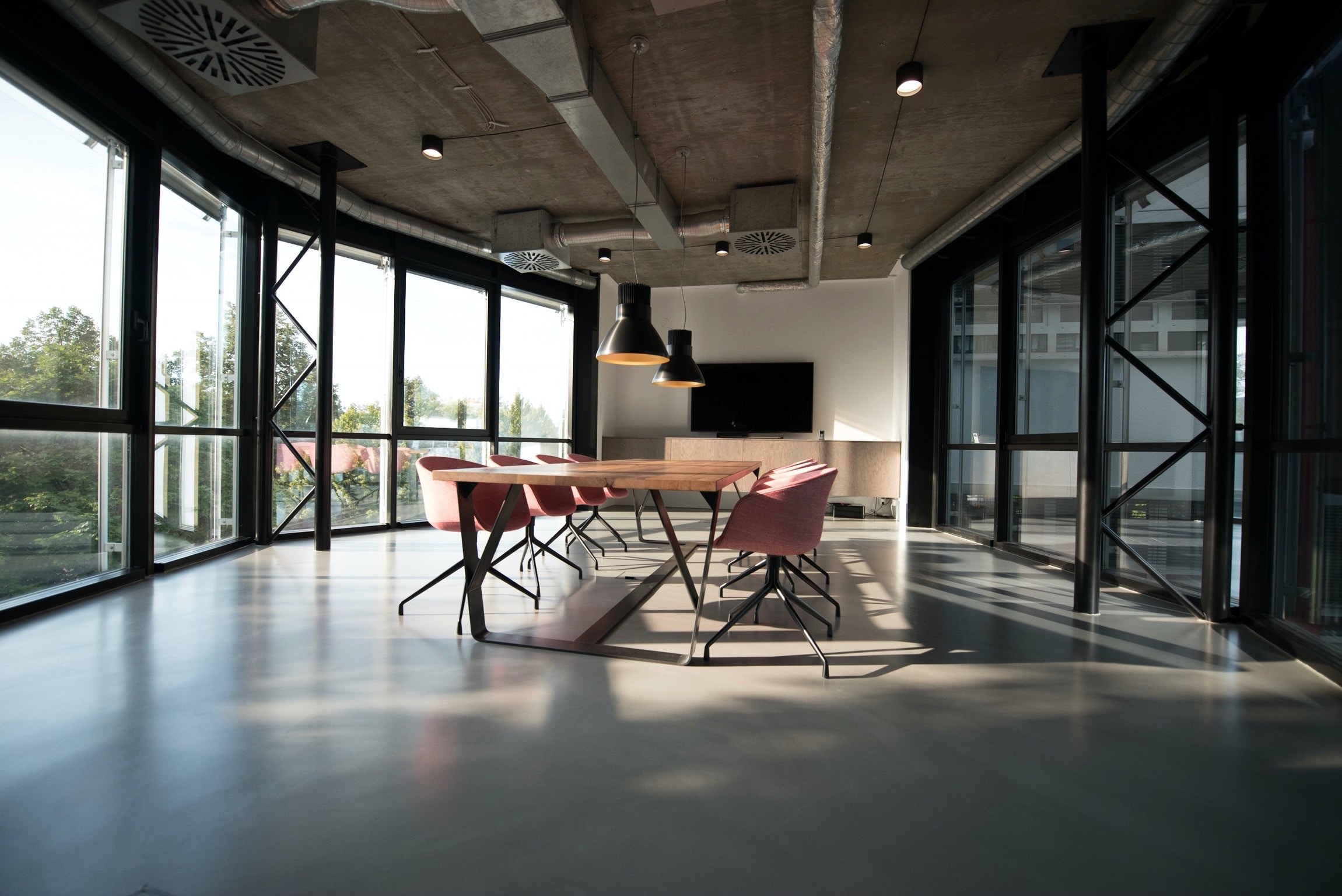 industrial style conference room with TV on wall and pink chairs