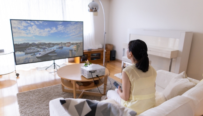A woman watching something on her projector with a very vivid image in a bright room
