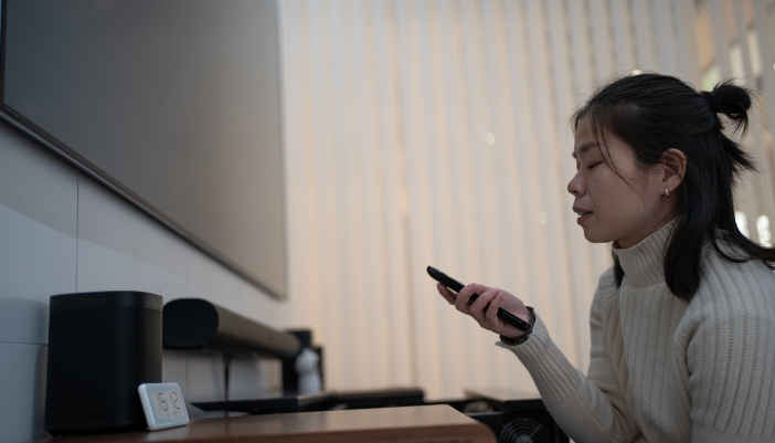 Elec_Classic-Films-Modern-Sound_2.jpg A woman turning on the TV with a soundbar and satellite speakers hooked up