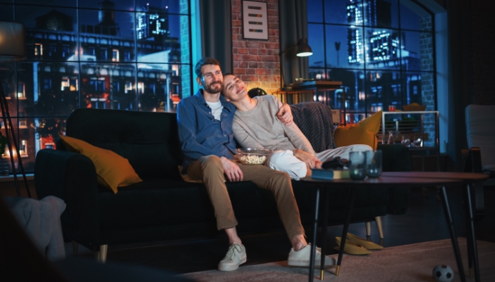A couple relaxing at home watching tv with popcorn