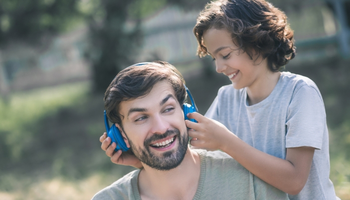 A little boy placing headphones on his father