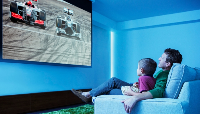 A father and son are watching racing with crystal clear picture from a projector