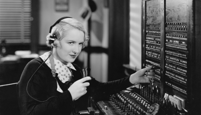 A retro image of a woman working a switchboard with headphones