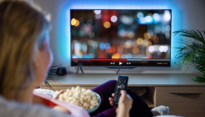 A closeup of someone watching TV with bias lighting behind the TV