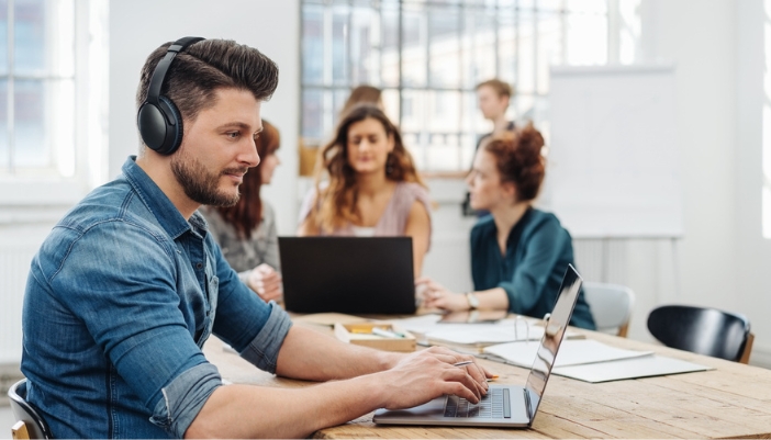 A man uses noise cancelling headphones at work to concentrate.
