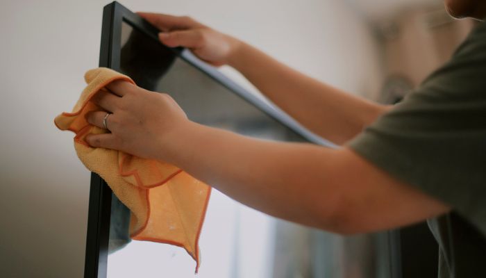 a person cleaning tv with a microfiber cloth