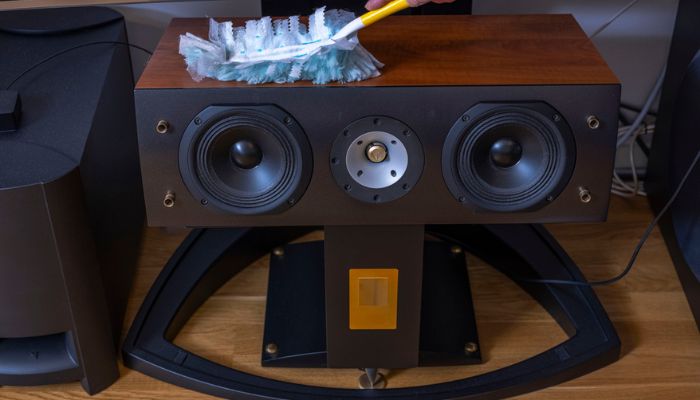 hand dusting off speaker
