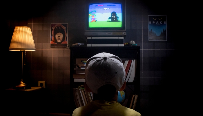 Kid playing old-school 8-bit gaming system on small TV