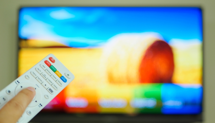 Someone adjusting colors on a TV with a remote