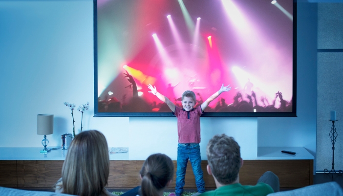 A family streaming a concert on their home theater projector in 4K