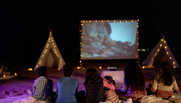 Family watching movie outside on the beach