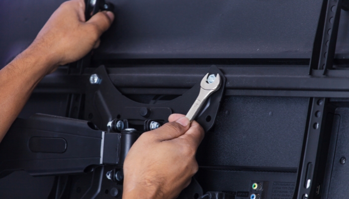 Closeup of someone tightening the bolts on the wall mount