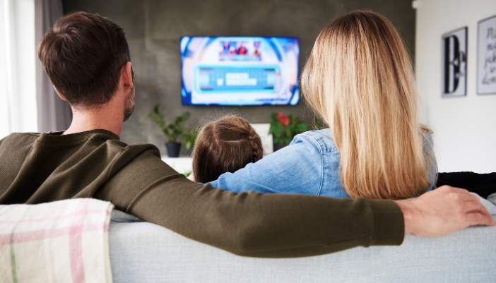 Family watching TV that is mounted on the wall