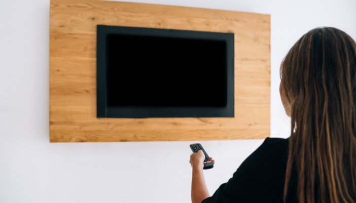 A woman is turning her TV on
