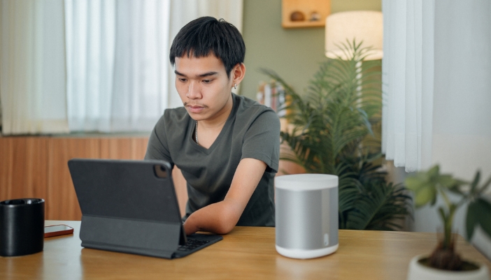 A man using a smart speaker while working on his computer