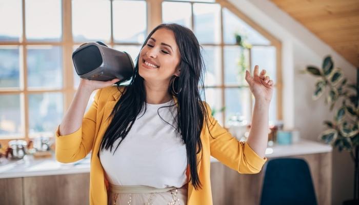 woman dancing while holding speaker