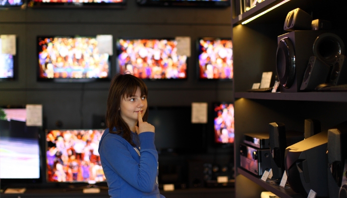 Young girl poring over speaker possibilities in store
