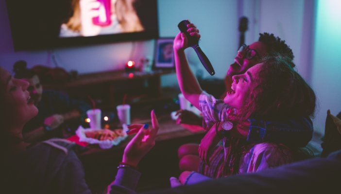 A group of friends singing along to songs in the living room