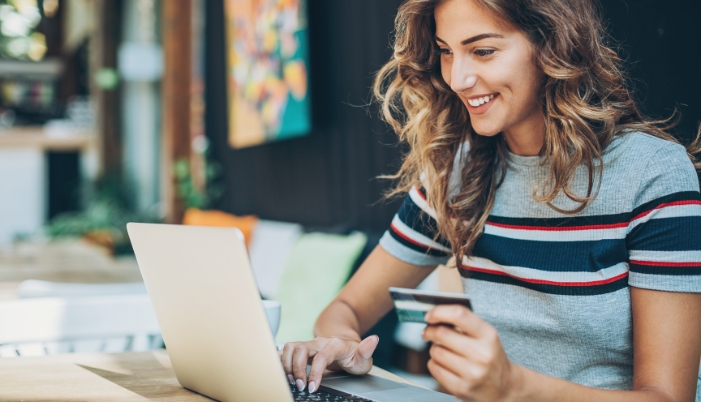 Concept image of a woman shopping online using her computer with her credit card in hand
