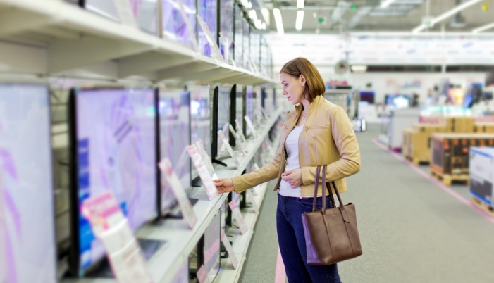 Side view of a woman checking out the TV specs in person in an electronics store