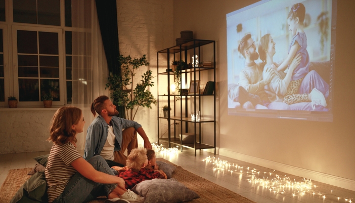 A family looking at their pictures on a big screen provided by projector