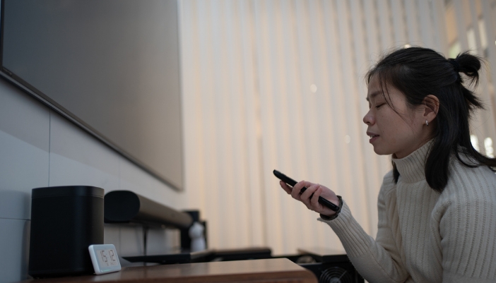 Closeup of an Asian woman setting up the sound on her TV with her soundbar and speakers