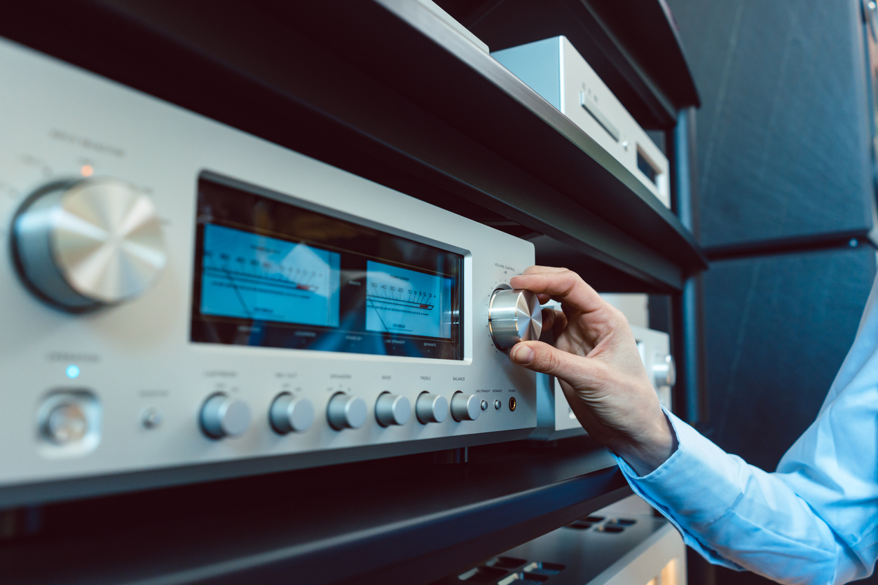 hand of woman turning up volume of Hi-Fi amplifier in her home