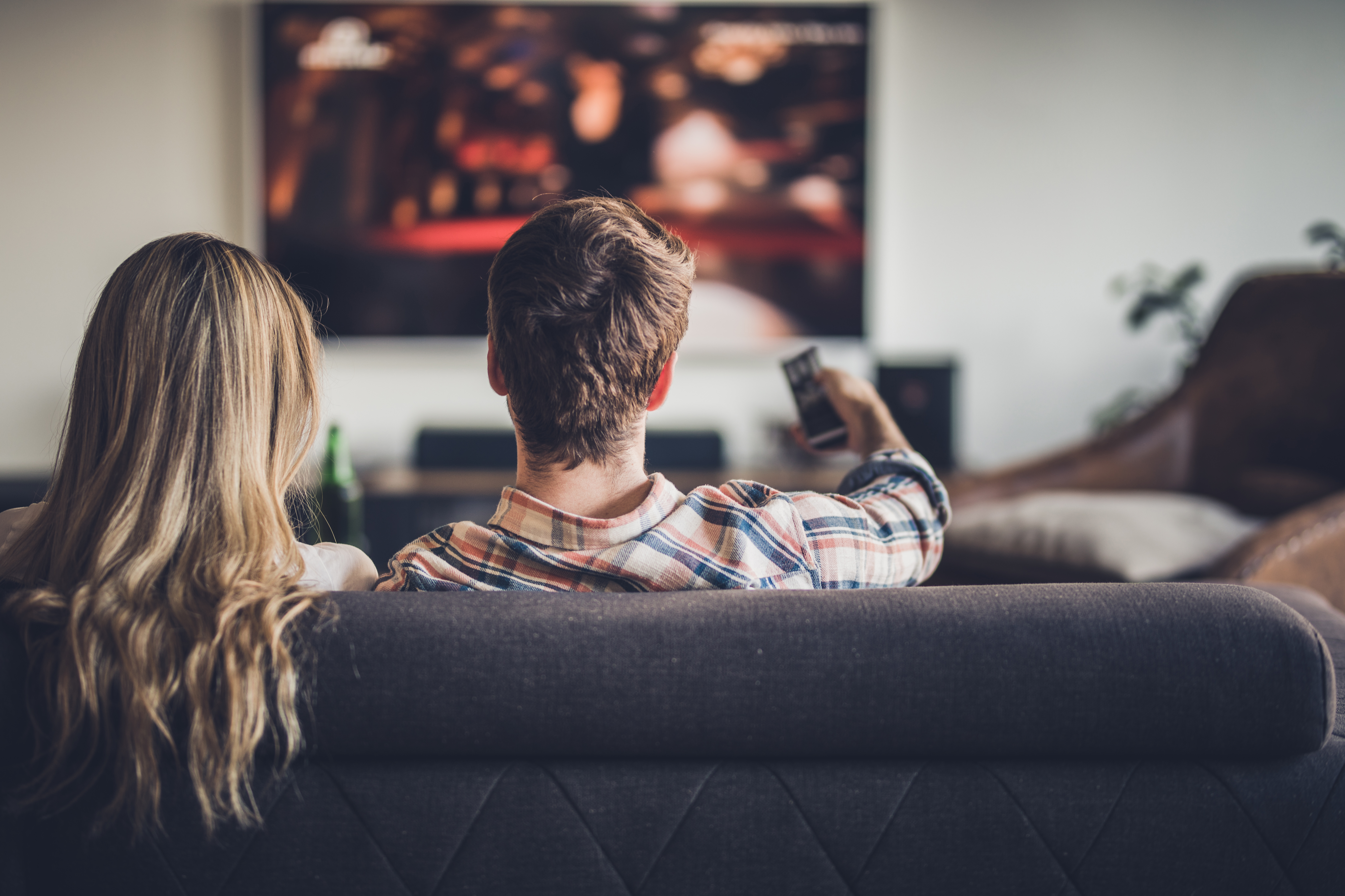 A couple sitting on a couch watching TV 