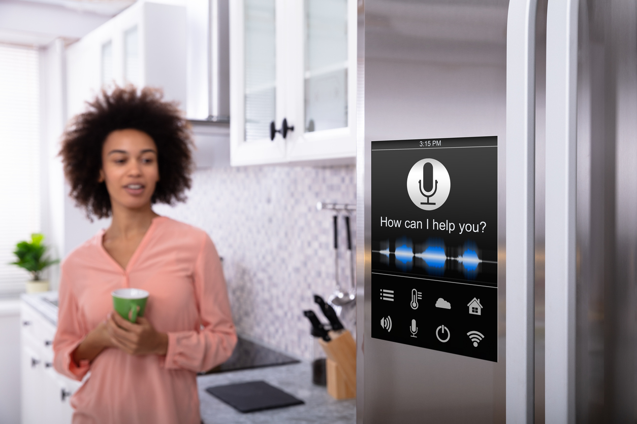 woman holding coffee mug in hand while looking at refrigerator with voice recognition function