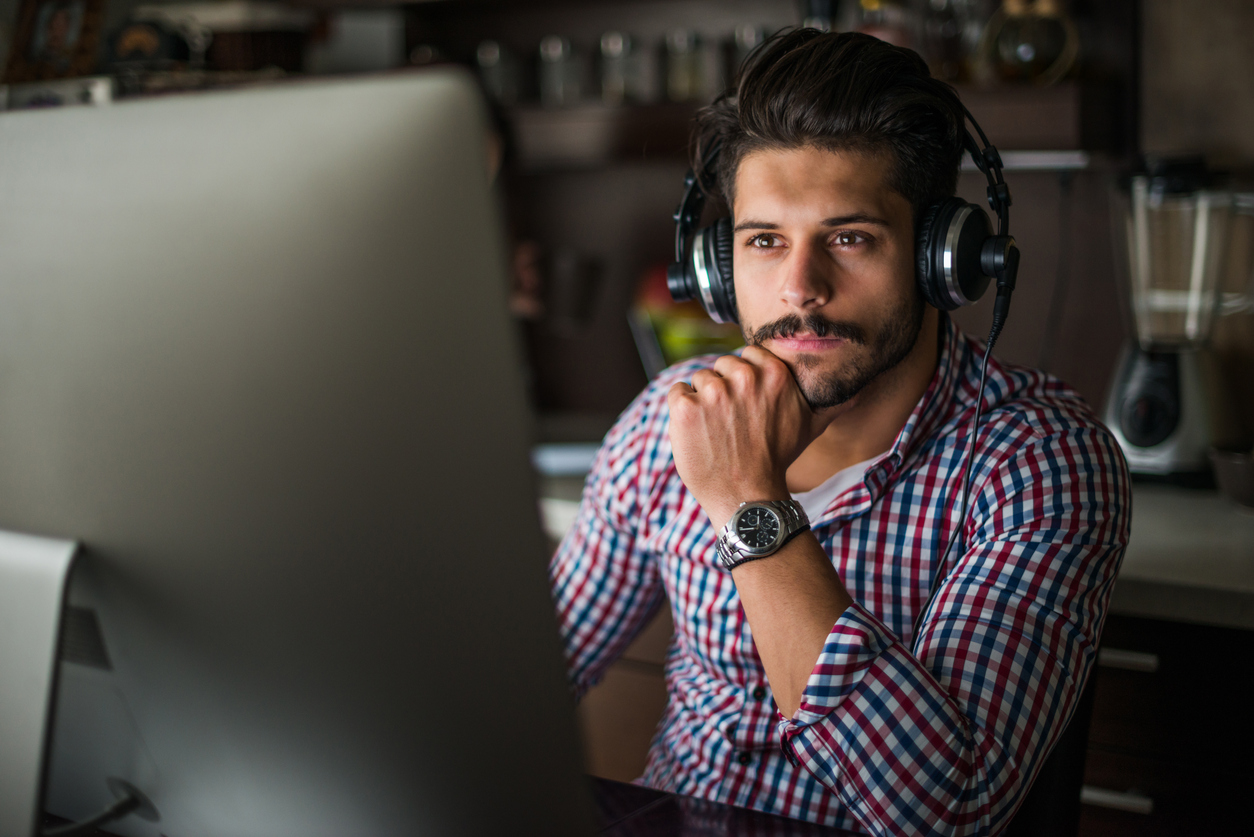 Man works in his home office wearing foldable over-the-ear headphones 
