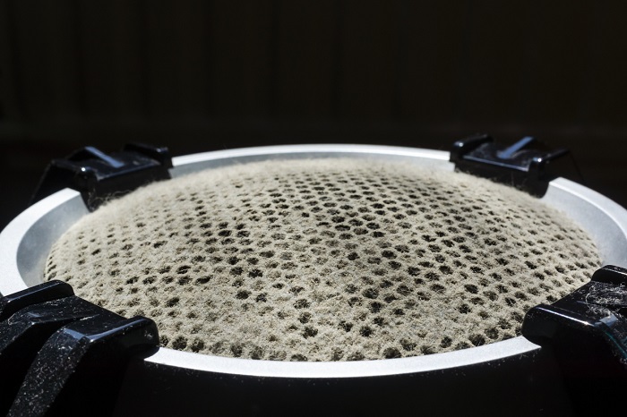 A hideous layer of dust on the speaker grill of a speaker