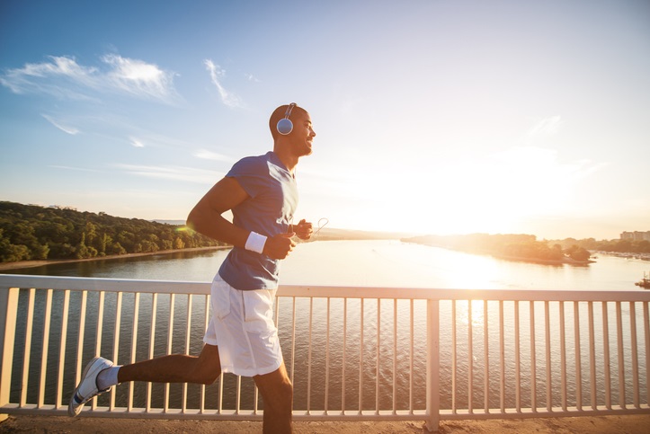 man running on a bridge along a river. Lens flare, warm tones.