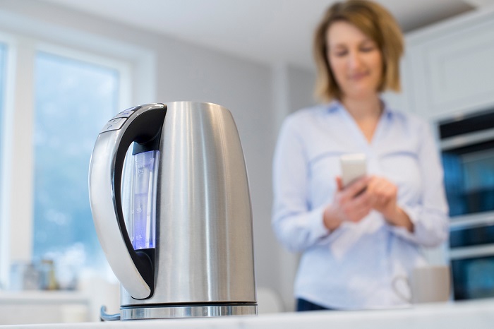 Woman controls smart kettle using app on phone