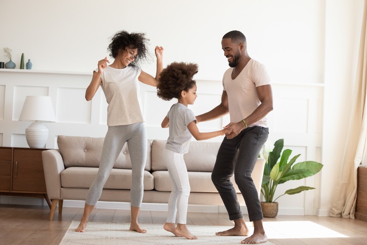 Two parents dance with their daughter at home