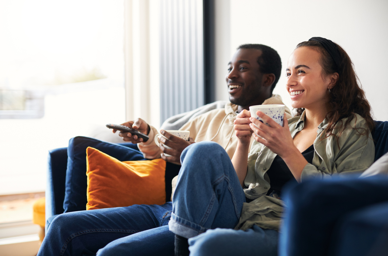 couple relaxing on sofa at home watching or streaming tv together