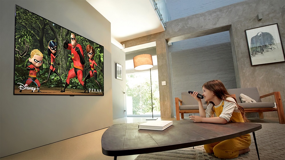 young girl speaks into tv remote to watch movie on LG TV