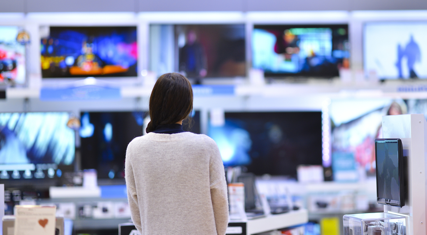 woman looking at a wall of televisions