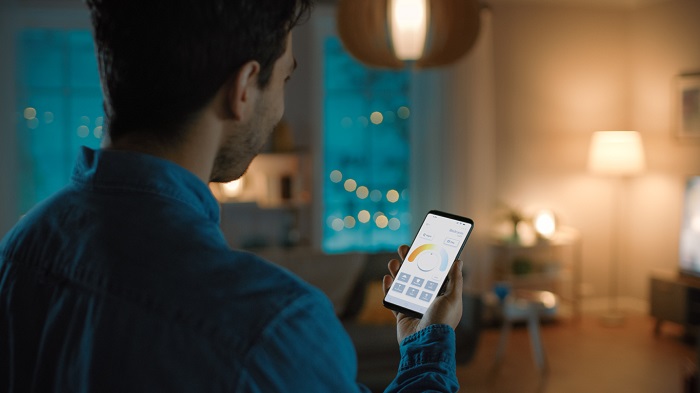 A man sets the lighting through an app on his phone.