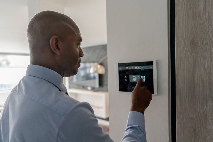 Man locking the door of a house using a home automation system.