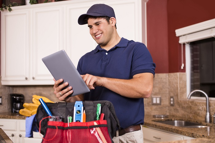 Service worker looking at a tablet with his tools on the counter.