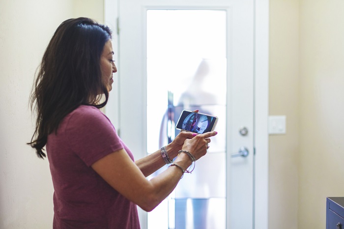 Woman checks tablet to see who is at her front door.