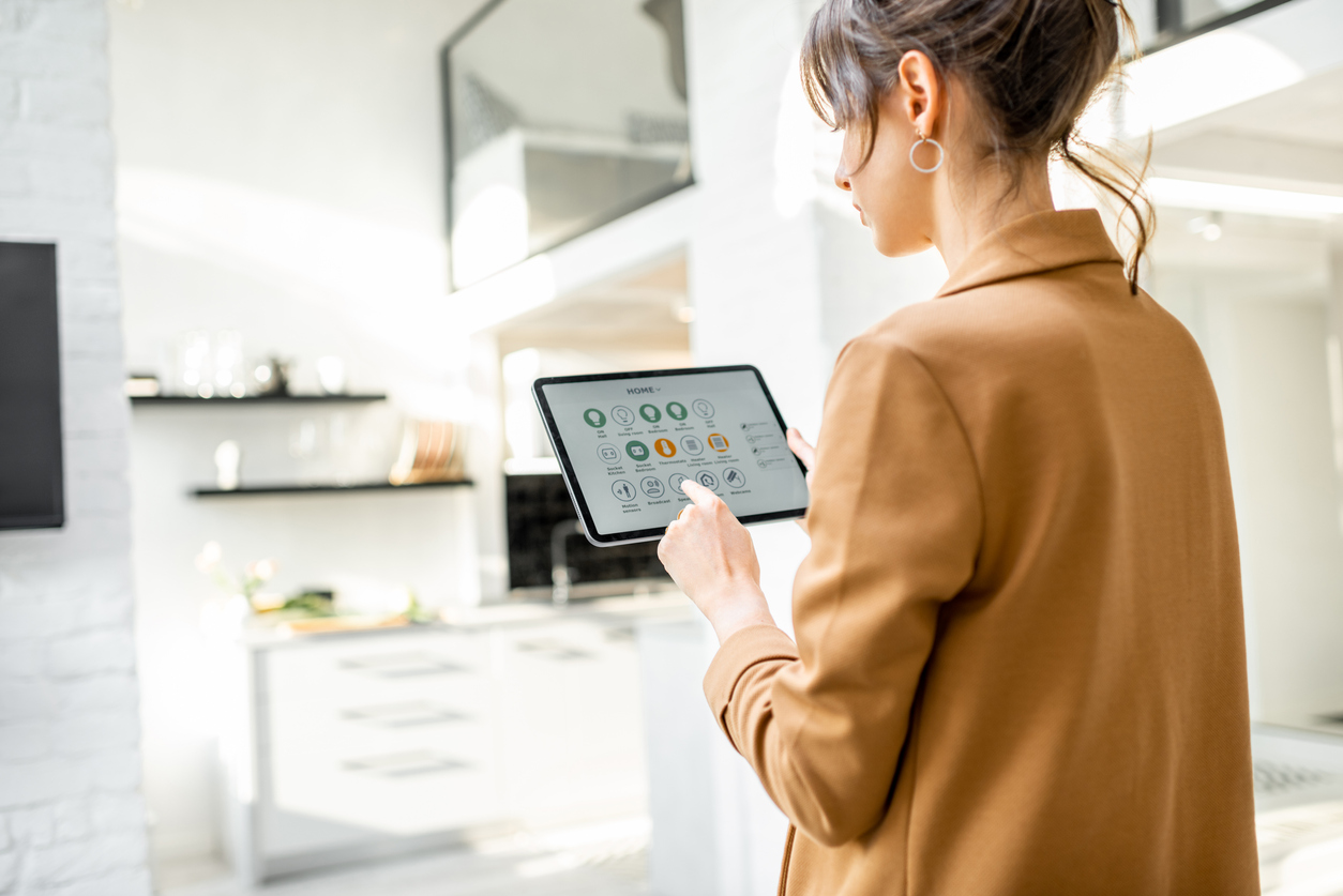 Woman uses smart home tablet controller at home