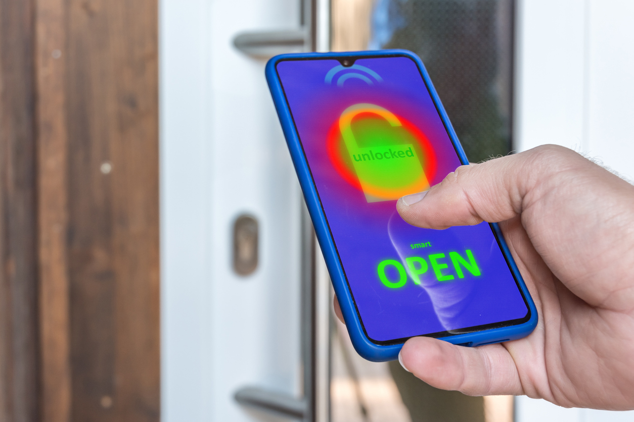 Hand holding a smart phone which is unlocking the smart lock on a front door