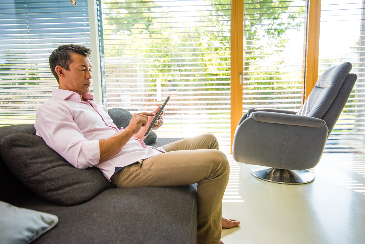 man controlling smart blinds with digital tablet