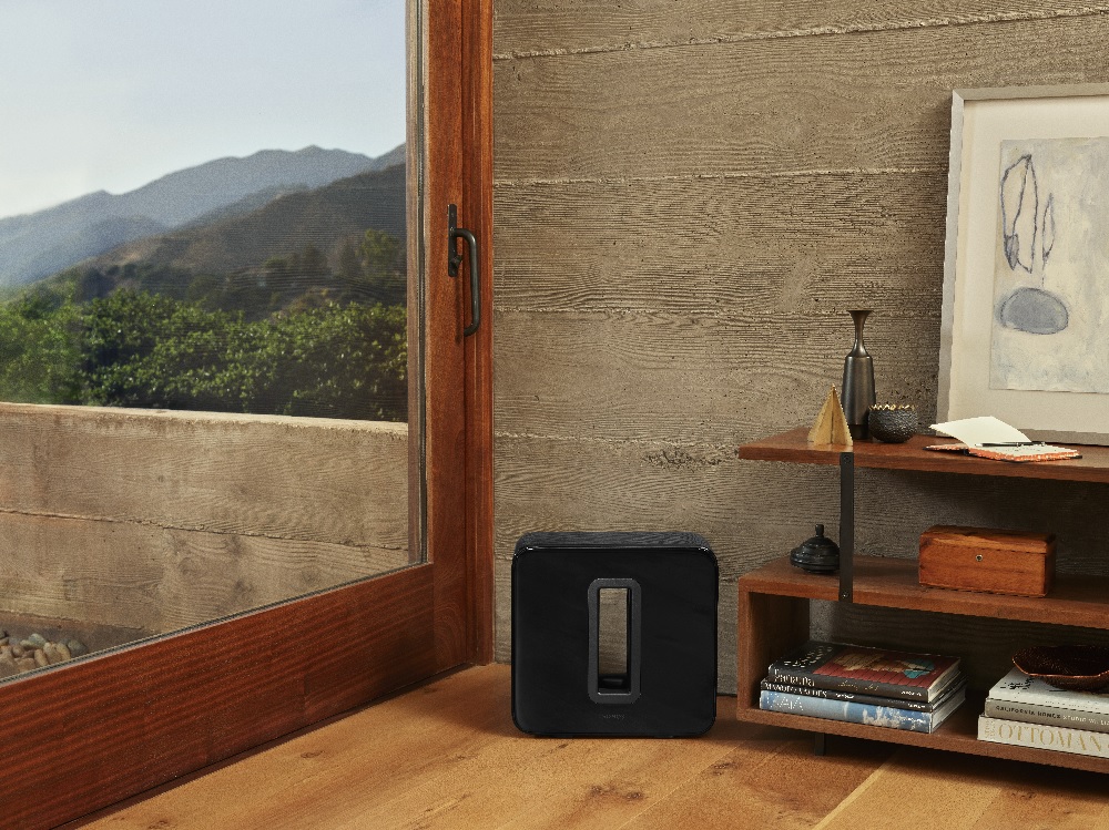 black Sonos subwoofer sits in the corner of a living room