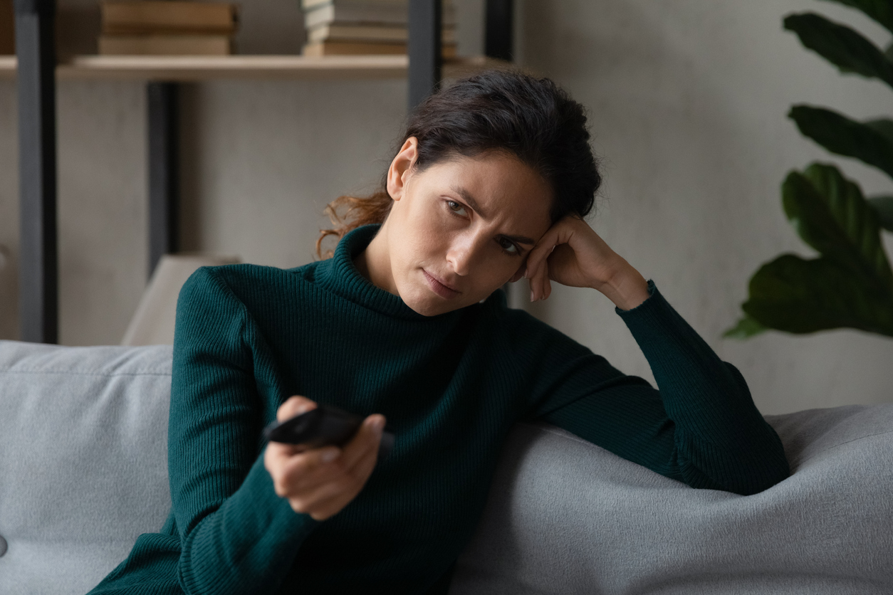 woman sit rest on sofa at home bored at home watching television