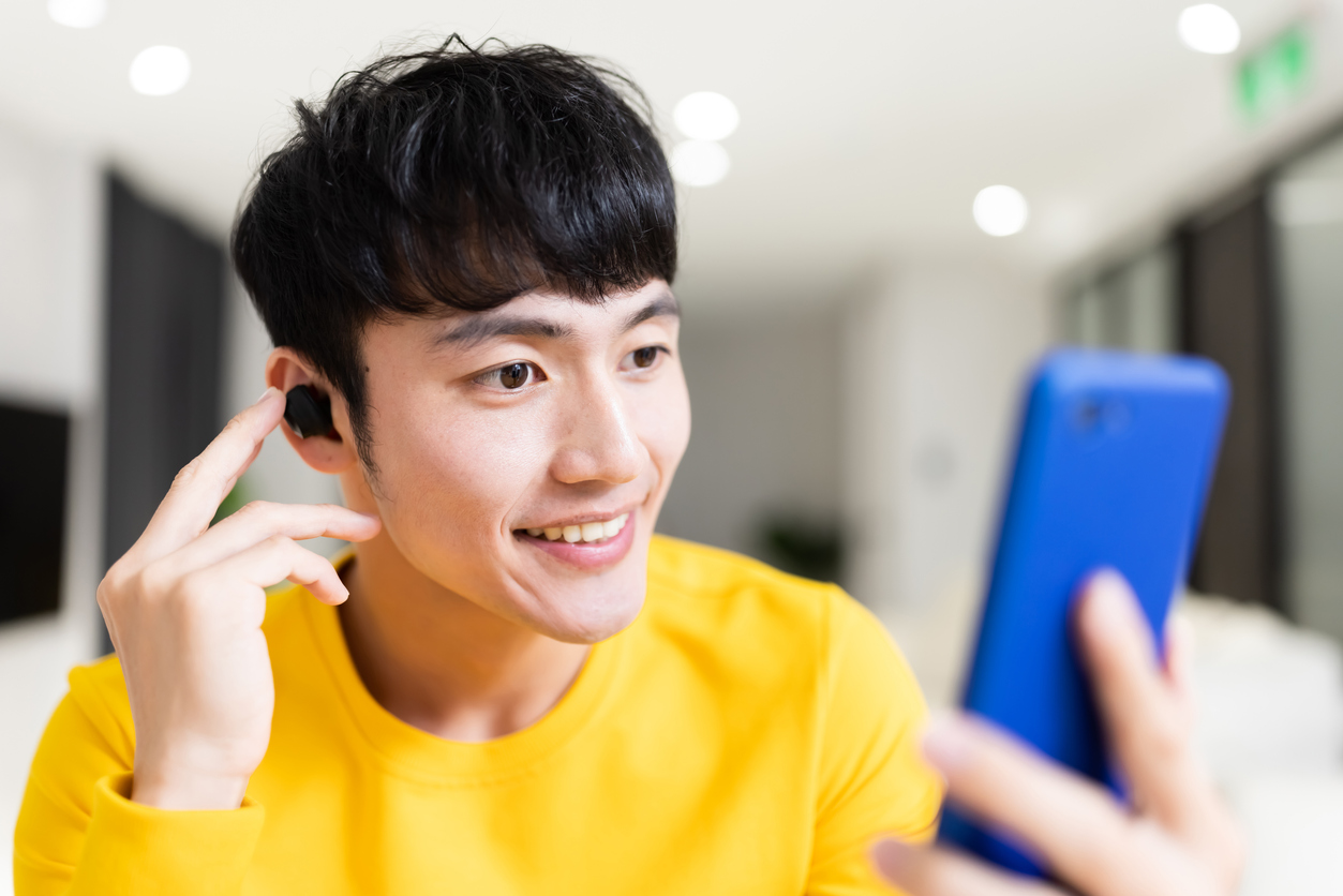 man wearing earbuds is having video chat on smartphone