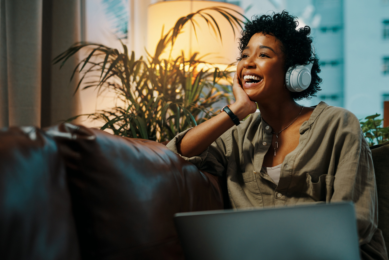 young woman wearing headphones while sitting at home with her laptop