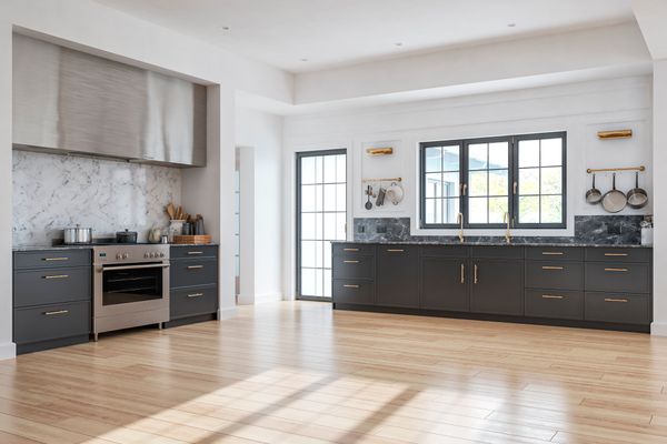 A modern kitchen with black cabinets and light wood flooring 