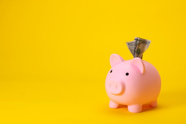 A pink piggy bank against a yellow background 